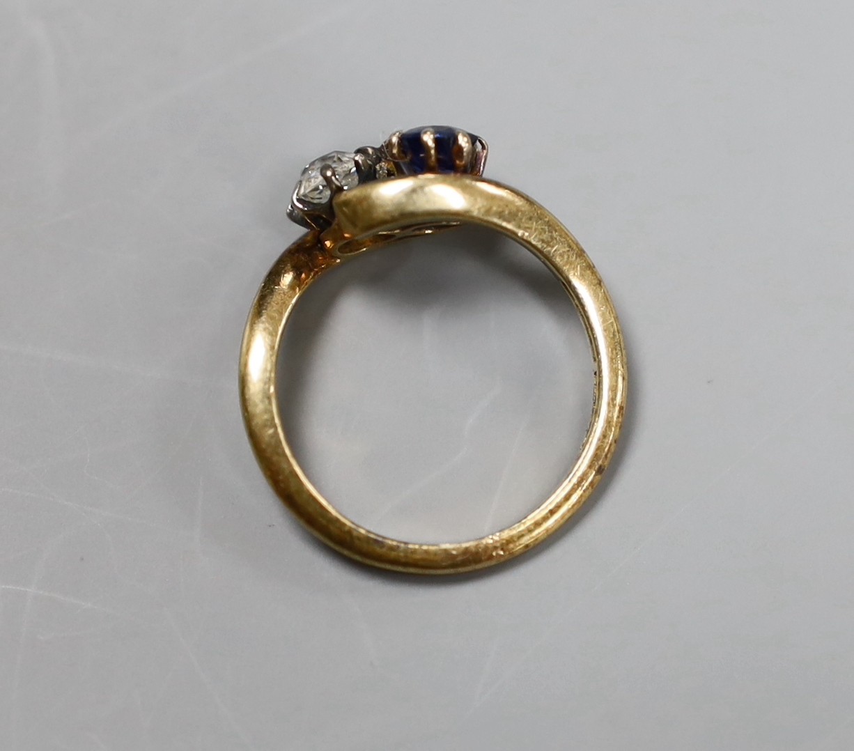 An early 20th century 18ct gold, sapphire and diamond two stone cross-over ring, size L, gross 3.2 grams